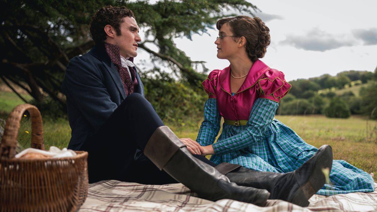 Dónal Finn as Tom and Ella Bruccoleri as Mary Hayward sitting together at a picnic.