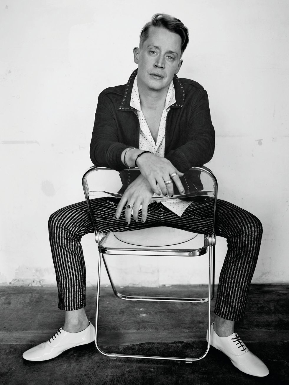Macaulay Culkin seated in a black-and-white photograph.