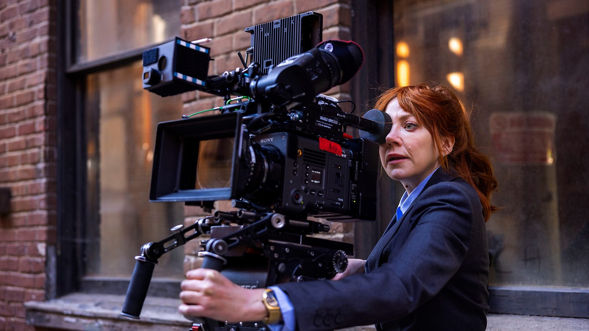 Diane Morgan as Philomena Cunk peers through a film camera in Cunk on Cinema.
