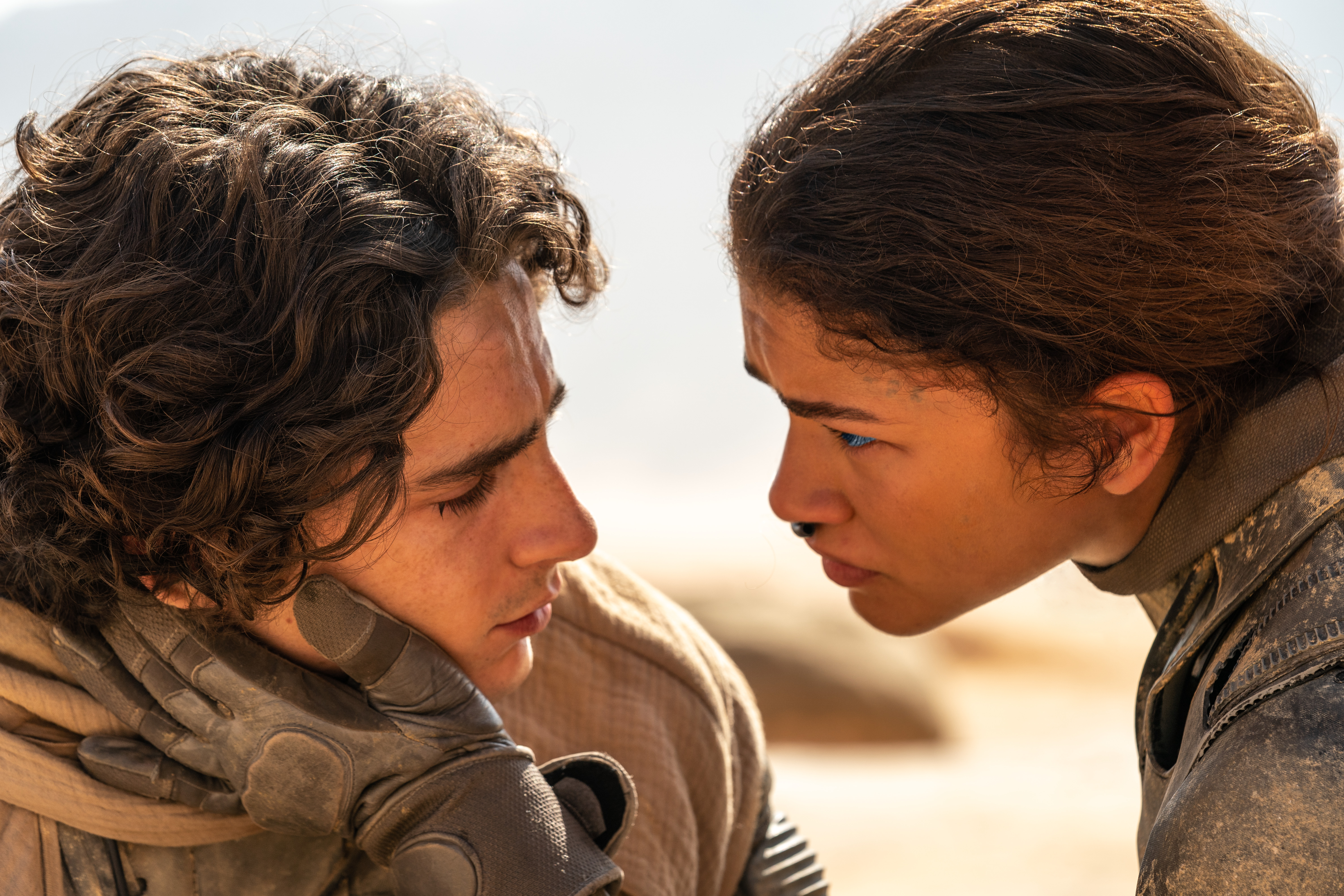 Timothée Chalamet as Paul Atreides and Zendaya as Chani lean close together in the desert in Dune: Part Two.