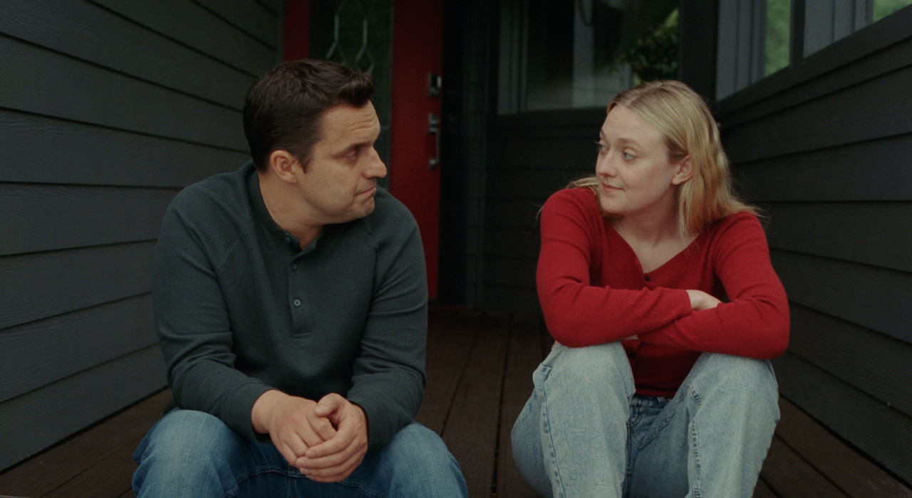 Jake Johnson and Dakota Fanning sit together on a house’s porch in The Sun Never Sets.